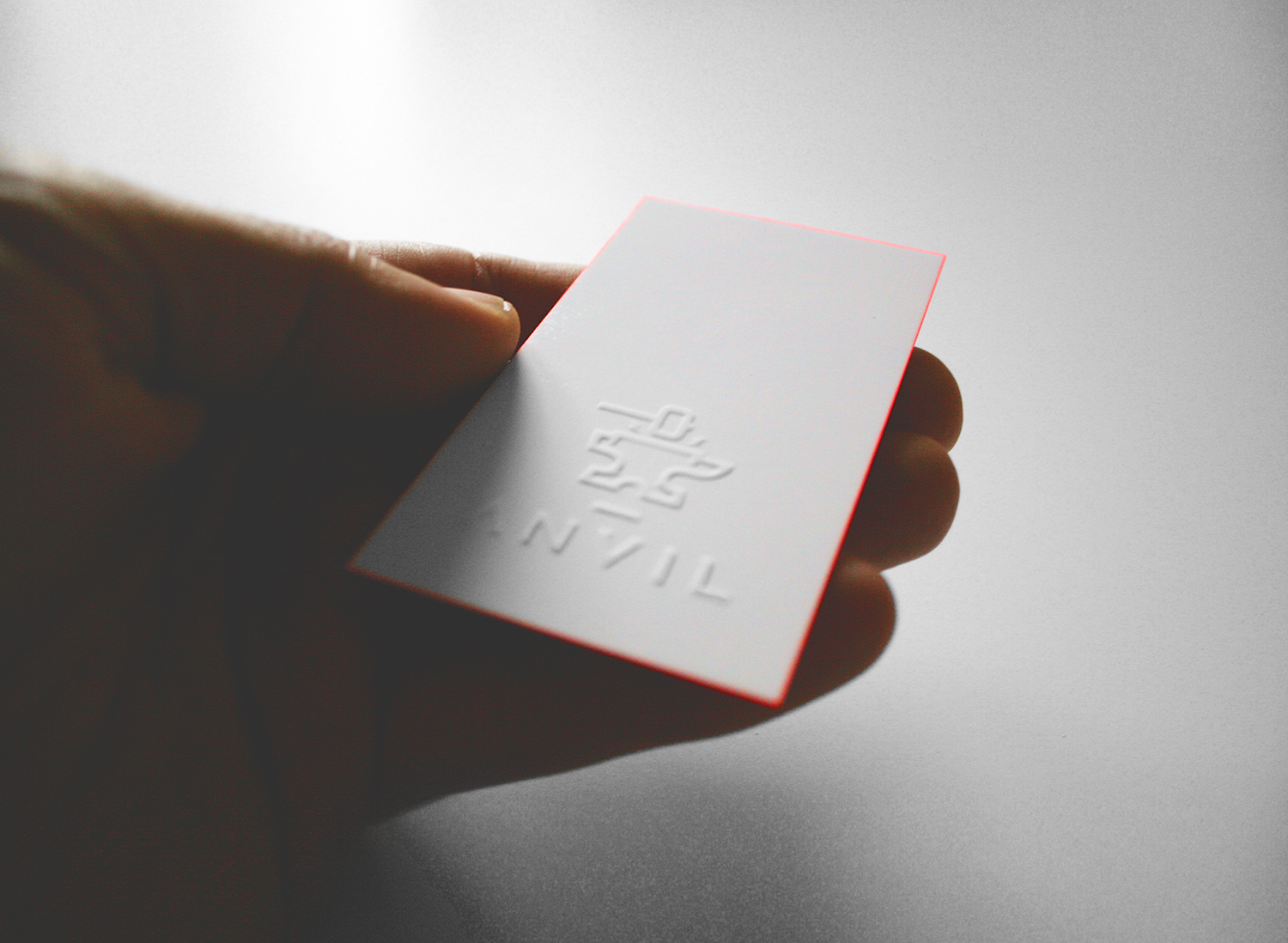 A photograph of a hand holding an Anvil business card